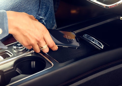 A hand is shown placing a smartphone on the available wireless charging pad. | Zeigler Lincoln of Kalamazoo in Kalamazoo MI