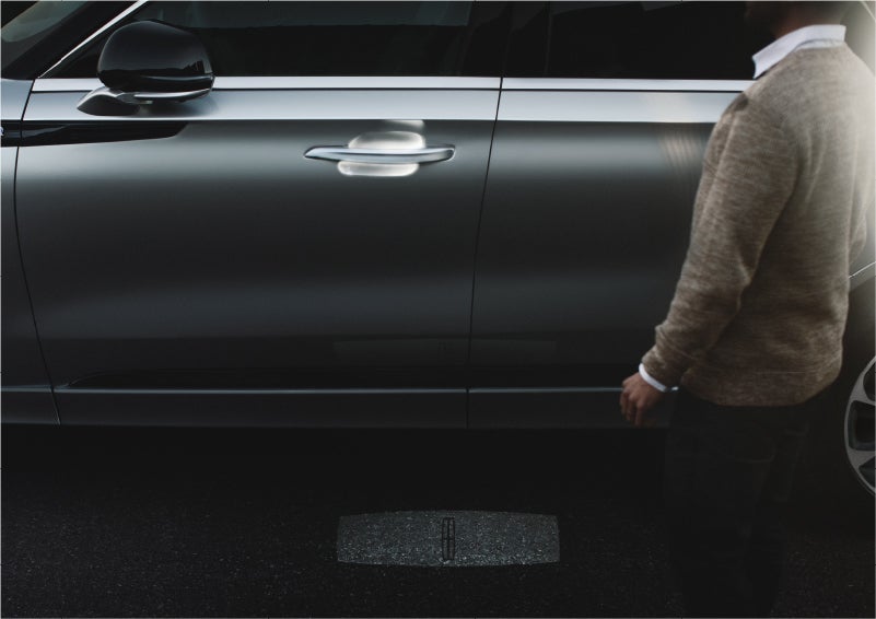 A person approaches a 2023 Lincoln Aviator® Grand Touring SUV as the Lincoln Embrace sequence of welcome lighting illuminates | Zeigler Lincoln of Kalamazoo in Kalamazoo MI