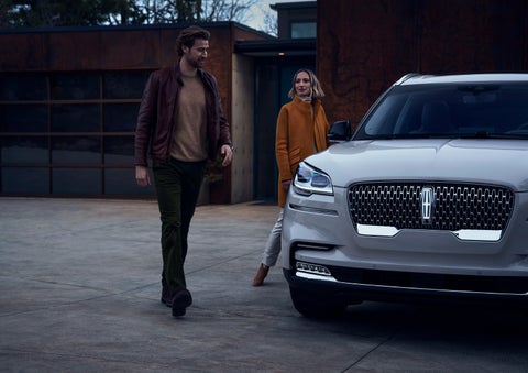A man and a woman approaching a 2024 Lincoln Aviator® SUV, which illuminates certain lights when they are close | Zeigler Lincoln of Kalamazoo in Kalamazoo MI