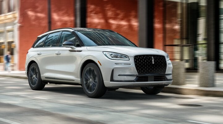 A white 2025 Lincoln Corsair® SUV with the Jet Appearance Package is being driven through a city.| Zeigler Lincoln of Kalamazoo in Kalamazoo MI