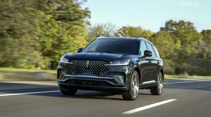 A 2026 Lincoln Black Label™ Aviator® SUV is being driven down a road lined with trees. | Zeigler Lincoln of Kalamazoo in Kalamazoo MI