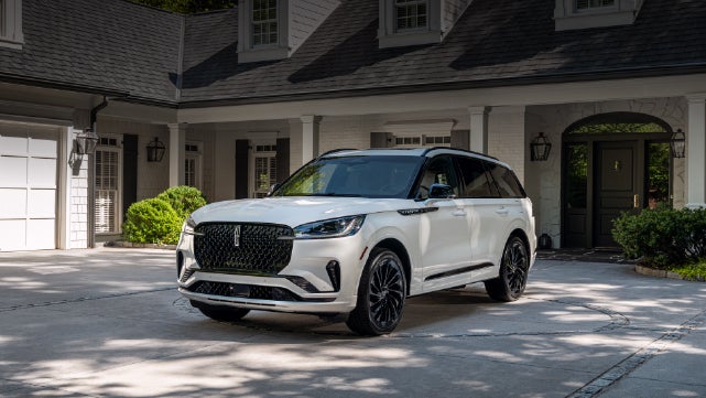A white 2026 Lincoln Aviator® SUV is parked in the driveway of a luxury home. | Zeigler Lincoln of Kalamazoo in Kalamazoo MI