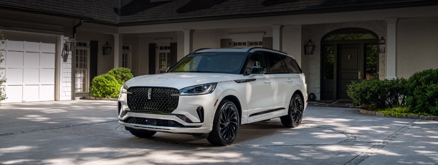 A white 2026 Lincoln Aviator® SUV is parked in the driveway of a luxury home. | Zeigler Lincoln of Kalamazoo in Kalamazoo MI