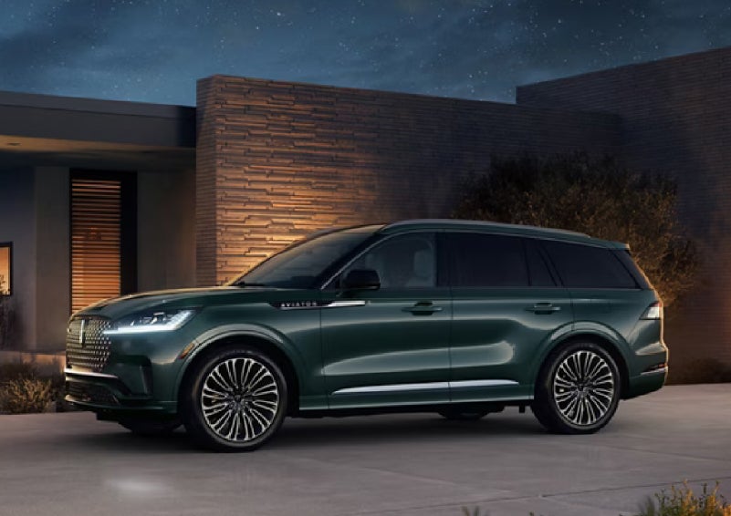 A green 2027 Lincoln Aviator® SUV is parked outside a contemporary home. | Zeigler Lincoln of Kalamazoo in Kalamazoo MI