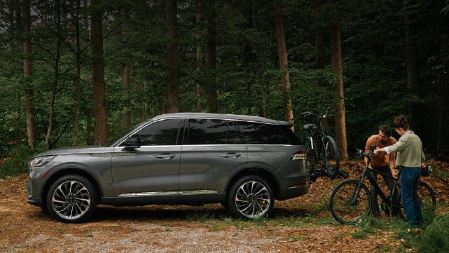 A father and son load e-bikes on a bike rack attached to a 2027 Lincoln Aviator® SUV. | Zeigler Lincoln of Kalamazoo in Kalamazoo MI
