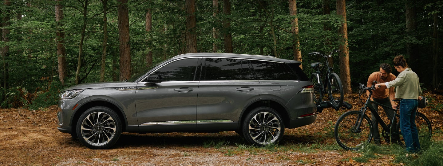 A father and son load e-bikes on a bike rack attached to a 2027 Lincoln Aviator® SUV. | Zeigler Lincoln of Kalamazoo in Kalamazoo MI